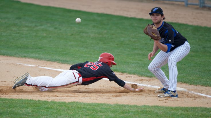 Ridgewater baseball player sliding into base while baseman is catching ball and protecting base.