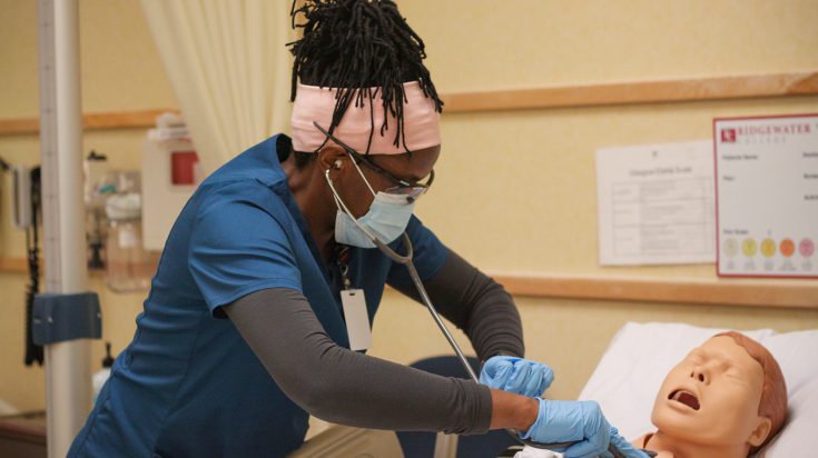 Diverse nursing student listening to patient chest