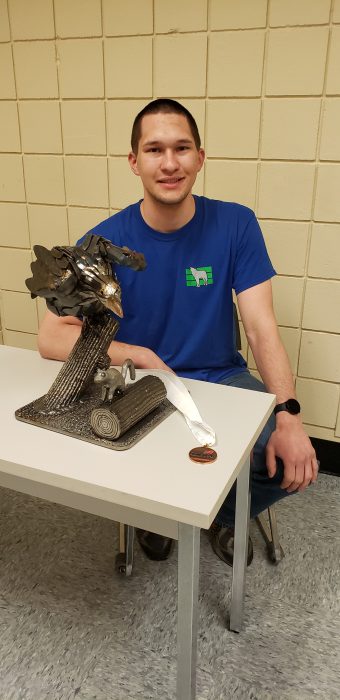 Photo of a student posing with an eagle sculpture