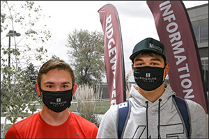 Two students stand outside with their masks on.