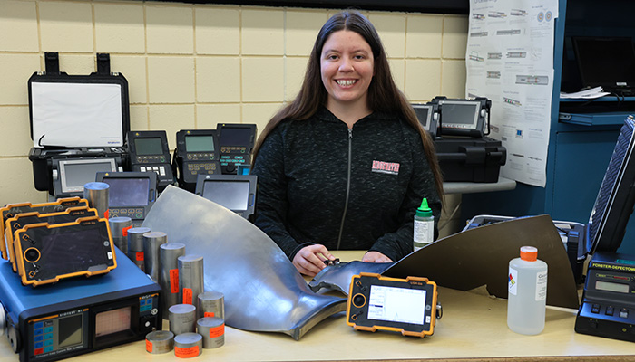 Photo of Bronte Carpenter with a selection of NDT tools in front of her
