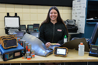Photo of Bronte Carpenter with a selection of NDT tools in front of her