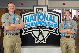 Josh and Emma pose in front of the IDEAL National Championship sign