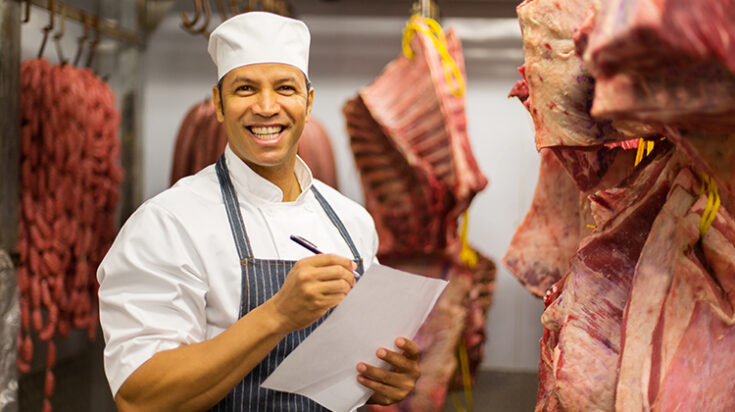 butcher counting stock of beef hanging in cold room