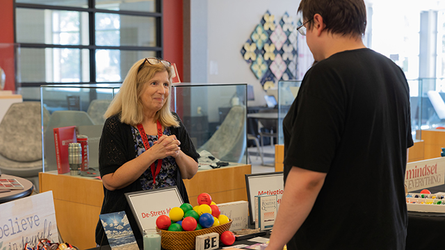 Image from Ridgewater's Start Strong event in Hutchinson: A staff member welcomes a student to their booth, offering stress relief services and support.