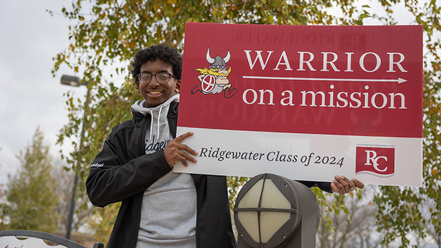 Student holding a large sign with the Ridgewater warrior, and it says Warrior on a mission. Ridgewater Class of 2024