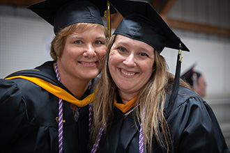 Three female faculty members in cap and gown at graduation