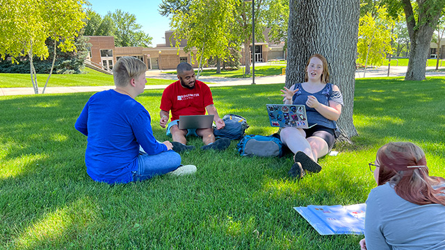 Photo of four students sitting outside on the Willmar campus.